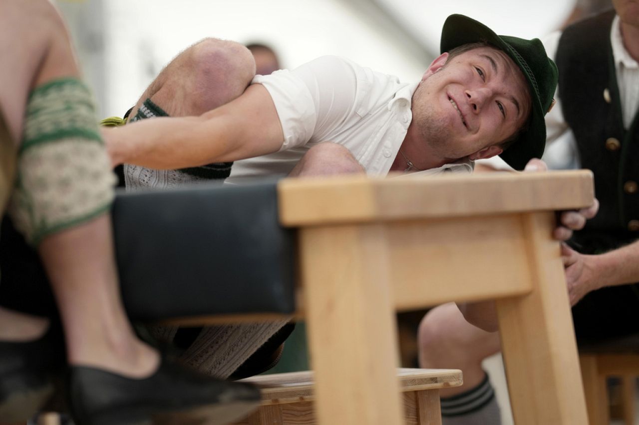 A man dressed in traditional clothes tries to pull his opponent over the table at the German Championships in Fingerhakeln in Bernbeuren, Germany, 12 May 2024.