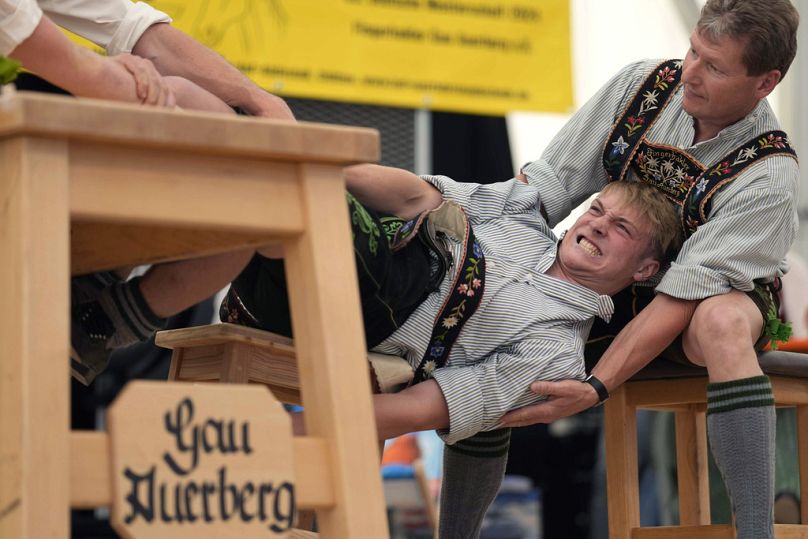 Un hombre vestido con ropa tradicional intenta tirar a su oponente por encima de la mesa en los Campeonatos Alemanes de Fingerhakeln en Bernbeuren, Alemania.