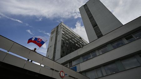 Мужчина размахивает национальным флагом у здания больницы, где проходит лечение премьер-министр Роберт Фицо, раненый в результате покушения, Братислава, 16 мая 2024 г.
