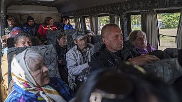 People sit in a bus after evacuation from Vovchansk,
