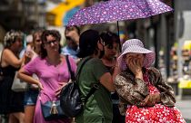 Uma mulher faz fila para comprar bilhetes de lotaria durante um dia quente em Madrid, em julho de 2022 - o ano mais quente de que há registo em Espanha.