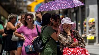 Uma mulher faz fila para comprar bilhetes de lotaria durante um dia quente em Madrid, em julho de 2022 - o ano mais quente de que há registo em Espanha.