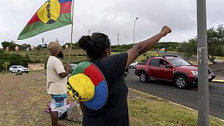 A woman waves a Kanak and Socialist National Liberation Front (FLNKS) flag in Noumea, New Caledonia, Wednesday May 15, 2024.