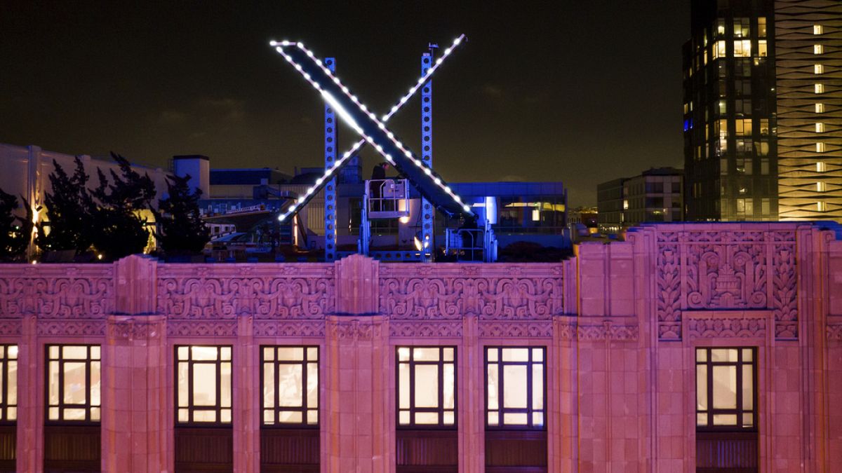 Workers install lighting on an "X" sign atop the company headquarters, formerly known as Twitter, in downtown San Francisco, on Friday, July 28, 2023.