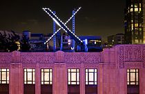 Workers install lighting on an "X" sign atop the company headquarters, formerly known as Twitter, in downtown San Francisco, on Friday, July 28, 2023.