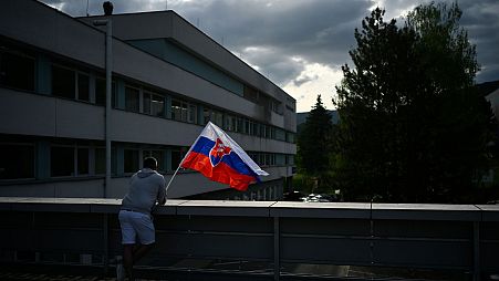 یک شهروند اسلواکی با پرچم این کشور در مقابل بیمارستان محل بستری نخست‌وزیر ترورشده