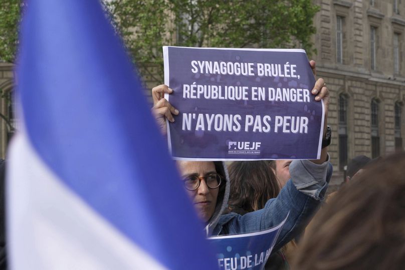 A demonstrators holds a poster reading « Synagogue burnt, Republic in danger, let's not be afraid » during a gathering in Paris, , May 17, 2024.