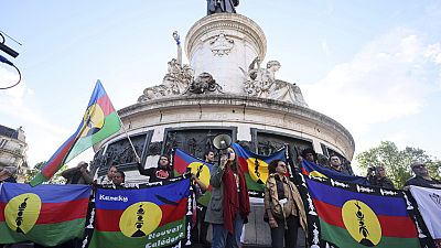 I manifestanti tengono in mano le bandiere del Kanak e del Fronte socialista di liberazione nazionale (FLNKS) durante un raduno a Parigi