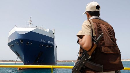 یک سرباز حوثی در تاریخ ۱۲ مه ۲۰۲۴ در مقابل کشتی اسرائیلی گلکسی که توسط حوثی‌ها در نزدیکی حدیده یمن،  توقیف شده بود