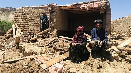An Afghan couple sit near to their damaged home after heavy flooding in Ghor province in western Afghanistan Saturday, May 18, 2024.