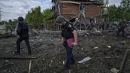 ضباط شرطة أوكرانيون يبحثون عن شظايا قنبلة انزلاقية أمام منزل متضرر بعد غارة جوية روسية على حي سكني في ��اركيف، أوكرانيا، 18 مايو 2024.