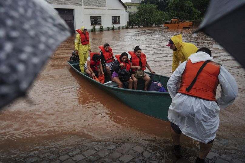 Bombeira transporta uma criança nos braços, resgatada das cheias em Porto Alegre