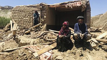 زوجان أفغانيان أمام منزلهما المتضرر بعد فيضانات غزيرة في مقاطعة غور بغرب أفغانستان، 18 مايو 2024.