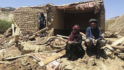 زوجان أفغانيان أمام منزلهما المتضرر بعد فيضانات غزيرة في مقاطعة غور بغرب أفغانستان، 18 مايو 2024.