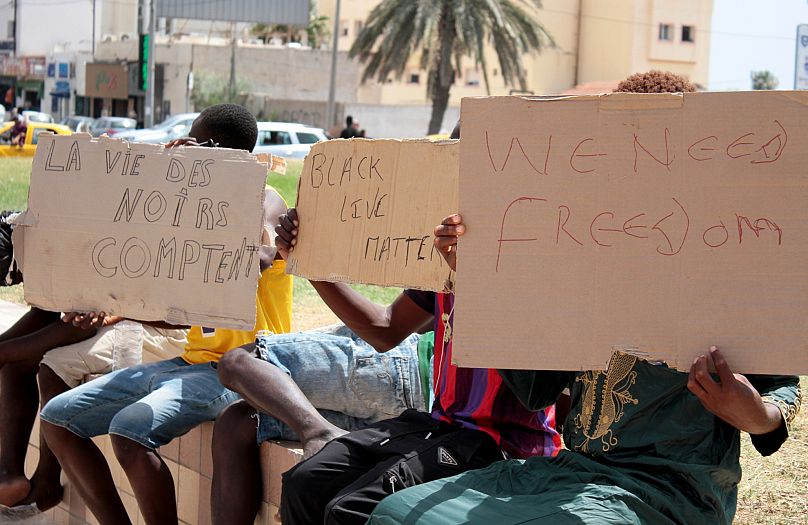 FILE - Migrants hold placards reading 'Black Lives Matter', left, in French, during a gathering in Sfax, Tunisia's eastern coast, on July 7, 2023.