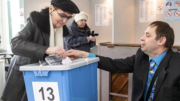 Un empleado de la comisión electoral ayuda a una mujer a emitir su voto en un colegio electoral en Tallin, Estonia, el 3 de marzo de 2019.