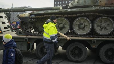 Архив: охранник убирает цветы с уничтоженного российского танка Т-72Б3, установленного как символ российского вторжения в Украину в 1-ю годовщину, Таллин, март 2023 г.
