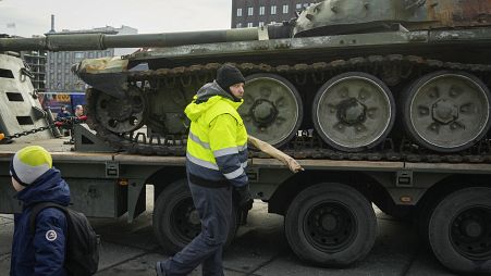 Архив: охранник убирает цветы с уничтоженного российского танка Т-72Б3, установленного как символ российского вторжения в Украину в 1-ю годовщину, Таллин, март 2023 г.
