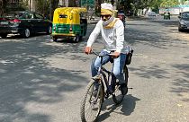 A cyclist has his head wrapped in a cotton scarf as protection from the heat in ]Delhi, India, 18 May, 2024.