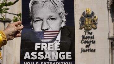 متظاهر يحمل ملصقًا لمؤسس ويكيليكس جوليان أسانج خارج المحكمة العليا في لندن