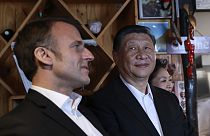 Chinese President Xi Jinping, right, watches French President Emmanuel Macron in a restaurant, Tuesday, May 7, 2024