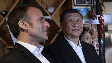Chinese President Xi Jinping, right, watches French President Emmanuel Macron in a restaurant, Tuesday, May 7, 2024