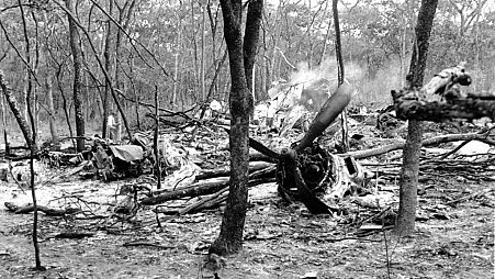 FILE - In this Sept. 19, 1961, file photo, searchers walk through the scattered wreckage of a DC6B plane in a forest near Ndola, Zambia.