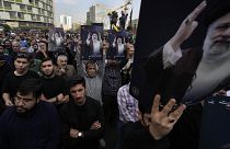 People hold up posters of Iranian President Ebrahim Raisi during a mourning ceremony for him at Vali-e-Asr square in downtown Tehran, Iran, Monday, May 20, 2024. 