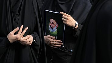 İranlı bir kadın Tahran'da Reisi için düzenlenen yas töreni sırasında onun posterini tutuyor