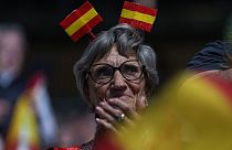 Uma apoiante com uma bandeira espanhola na cabeça participa num comício do partido de extrema-direita espanhol Vox "Europa Viva 24" em Madrid, Espanha, no domingo, 19 de maio 