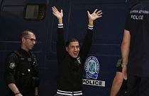 Göçmen kaçakçılığından yargılanan dokuz Mısırlıdan biri, Yunanistan'ın güneybatısındaki Kalamata'da mahkemeden çıkarken basın mensuplarına el sallıyor.21 Mayıs 2024