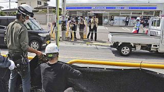 Des ouvriers installent un immense écran noir sur un trottoir de la ville de Fujikawaguchiko, dans la préfecture de Yamanashi, au centre du Japon, le mardi 21 mai 2024. 