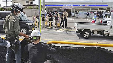 Workers set up a huge black screen on a stretch of sidewalk at Fujikawaguchiko town, Yamanashi prefecture, central Japan Tuesday, May 21, 2024. 