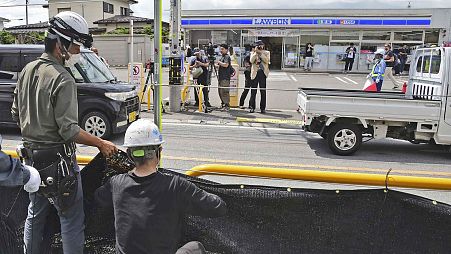 Trabajadores instalan una enorme pantalla negra una acera en la ciudad de Fujikawaguchiko, prefectura de Yamanashi, en el centro de Japón, el martes 21 de mayo de 2024. 