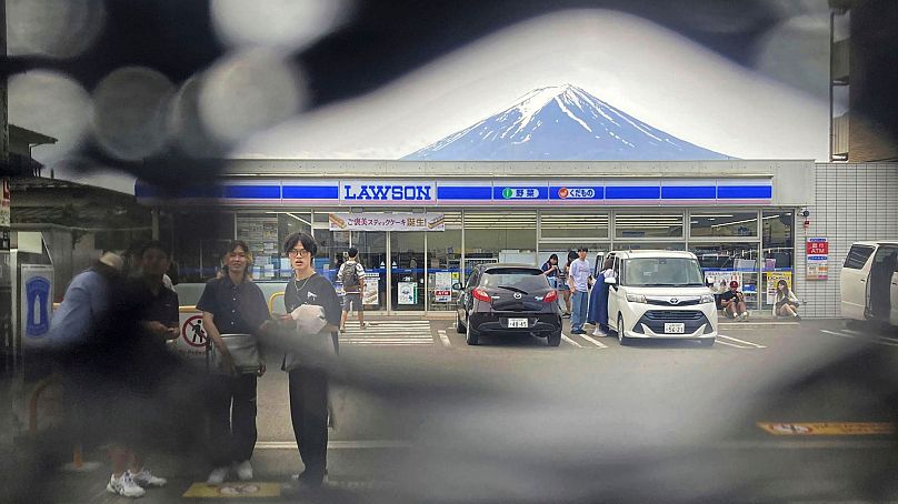 Mt. Fuji is seen through a hole on a black screen installed across from a convenience store in Fujikawaguchiko town, Yamanashi prefecture, central Japan on 24 May 2024. 