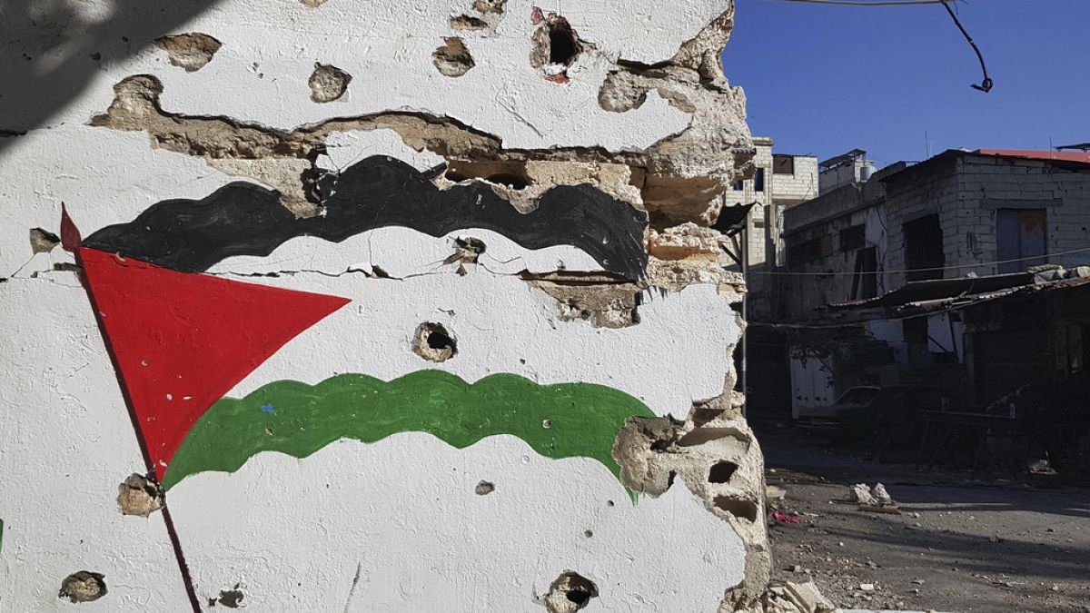 Egy golyó ütötte lyukakkal teli falra festett palesztin zászló a libanoni Szidon déli kikötőváros közelében lévő Ein el-Hilweh palesztin menekülttáborban, 2023-ban. 