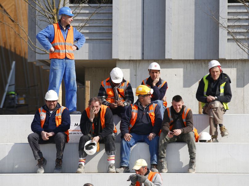 Workers sit near pavilions under construction during Italian Premier Matteo Renzi's visit at the Expo site in Rho, March 2015