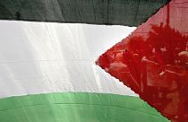 Palästinensische Arbeiter werden durch eine palästinensische Flagge in der Westjordanland-Stadt Ramallah gesehen, 30. Mai 2006