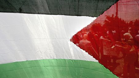 Palestinian workers are seen through a Palestinian flag in the West Bank town of Ramallah, 30 May 2006