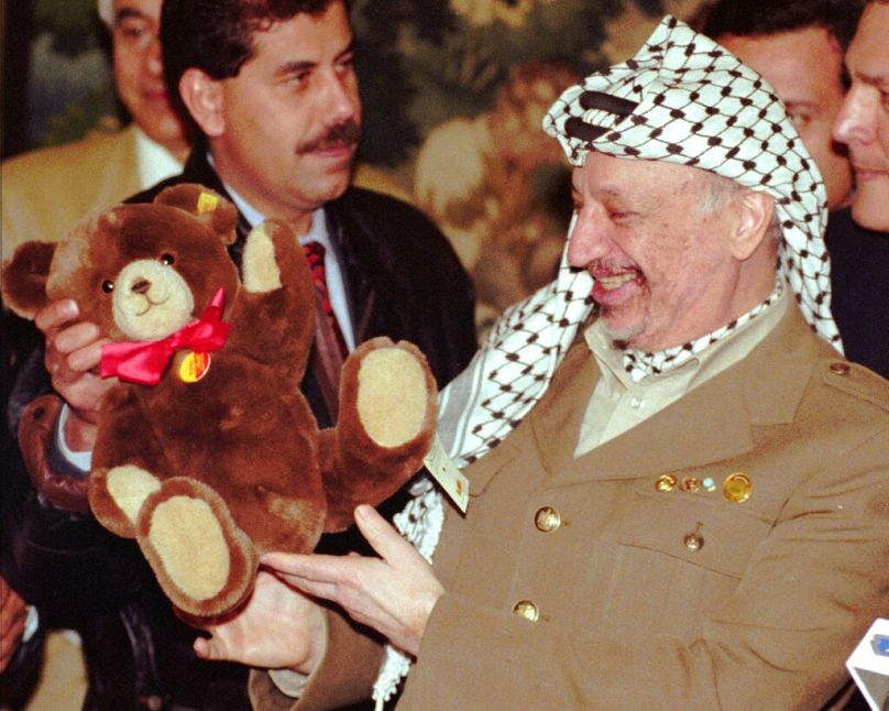 O líder da OLP, Yasser Arafat, segura um urso de peluche que recebeu como presente regional do primeiro-ministro do estado alemão de Baden-Wuerttemberg, Erwin Teufel, em Estug