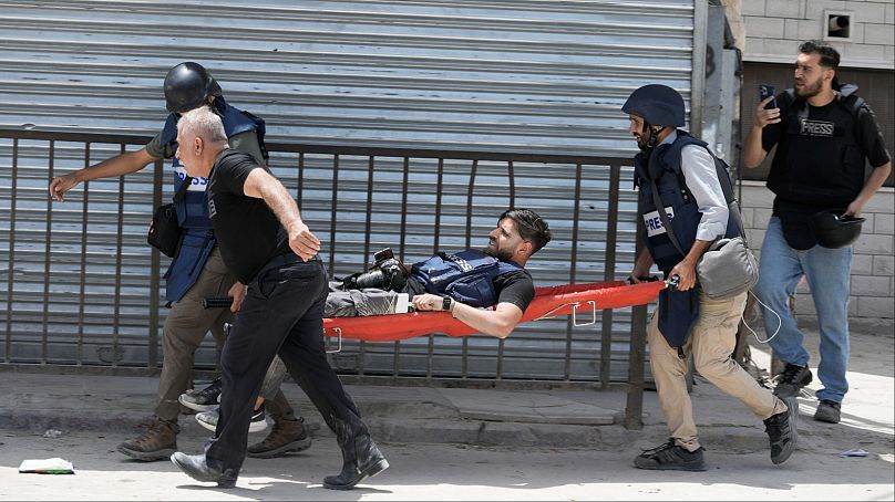 صحفيون يحملون زميلهم بعد إصابته برصاصة في ساقه خلال توغل قوة إسرائيلية في مخيم جنين للاجئين بالضفة الغربية، الثلاثاء 21 مايو 2024.