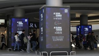 Un grupo de personas pasa junto a las pantallas que anuncian la próxima Cumbre sobre Inteligencia Artificial en Seúl (Corea del Sur).