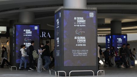 People pass by screens announcing the upcoming AI Seoul Summit in Seoul, South Korea.