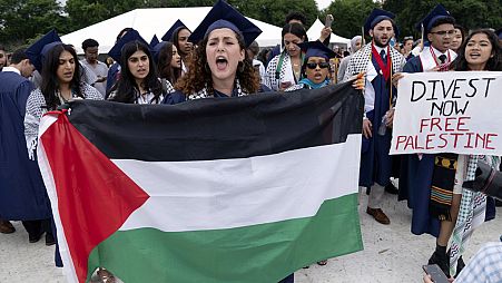 طلاب جامعة جورج واشنطن يحملون العلم الفلسطيني خلال احتجاج مؤيد للفلسطينيين في حفل التخرج في واشنطن، 19 مايو، 2024.