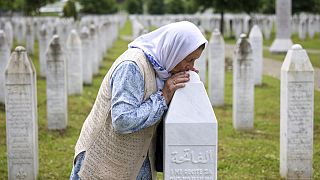 Una ciudadana bosnia besa la tumba de su hijo, víctima del genocidio de Srebrenica, en el Centro Memorial de Potočari, Bosnia-Herzegovina, el miércoles 22 de mayo de 2024.