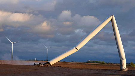 The remains of a tornado-damaged wind turbine touch the ground in a field, Tuesday, May 21, 2024, near Prescott, Iowa. 