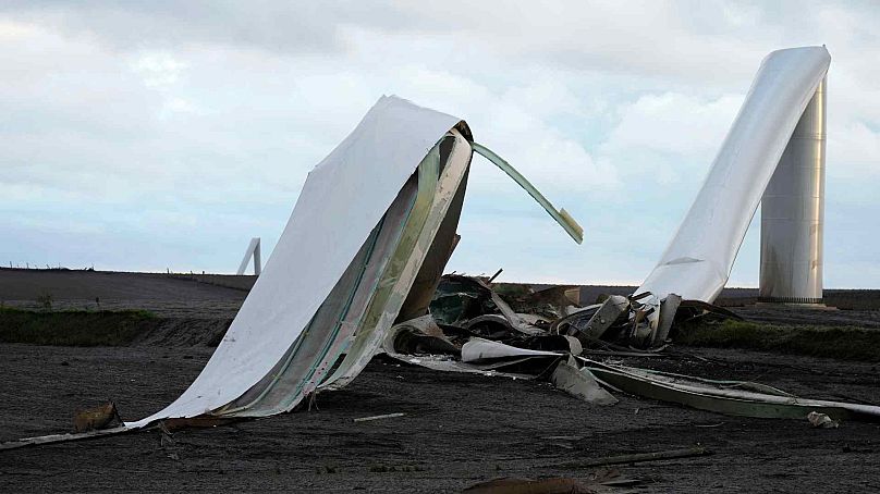 The remains of a tornado-damaged wind turbine touch the ground in a field, Tuesday, May 21, 2024, near Prescott, Iowa.