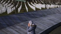 A woman prays next to the monument with names of those killed in the Srebrenica genocide, on International Holocaust Remembrance Day, in Potocari, 27 January 2024