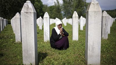 سيدة مسنة تزور ضريح ابنيها اللذين وقعا ضحية الإبادة الجماعية في سريبرينيتسا، في مركز النصب التذكاري في بوتوكاري، البوسنة، الأربعاء، 22 مايو/أيار 2024. 