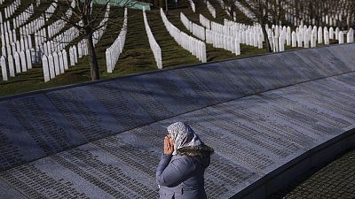 A woman prays next to the monument with names of those killed in the Srebrenica genocide, on International Holocaust Remembrance Day, in Potocari, 27 January 2024